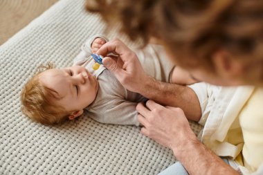 Kıvırcık, bekâr bir babanın bebeğini yatakta emzirirken görüntüsü.