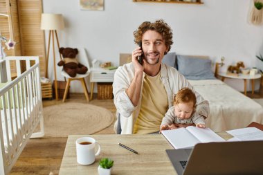 Çocuk kucağında mutlu bir adam akıllı telefonla konuşurken ve evde çalışırken, iş hayatı dengesi