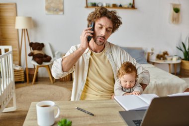 Baba bebeğini kucağında tutarken akıllı telefonla konuşuyor ve evde çalışıyor. İş hayatı dengesi.