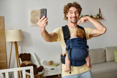 joyful father taking selfie with sleeping baby in carrier, fatherhood and modern parenting concept clipart