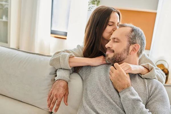 Happy Wife Kissing Head Smiling Husband Sitting Couch Closed Eyes — Stock Photo, Image