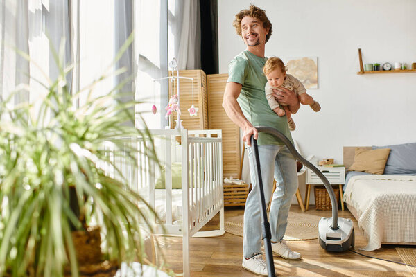 man multitasking housework and childcare, single father vacuuming apartment with infant boy in arms
