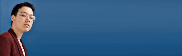 азиатский модный подросток в модном наряде, смотрящий в камеру на синем фоне, баннер