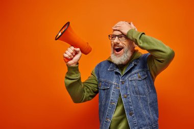 surprised jolly mature male model in vibrant stylish outfit posing with megaphone with hand on head clipart