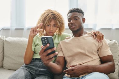 Mutlu Afro-Amerikan çifti akıllı telefondaki görüntülü konuşma sırasında işaret dilini kullanarak iletişim kuruyor.