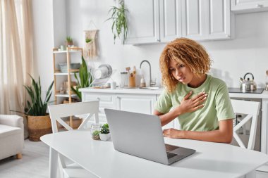 Kıvırcık Afrikalı Amerikalı kadın dizüstü bilgisayardaki video görüşmesi sırasında işaret diliyle lütfen diyor.