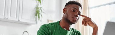 Yakışıklı ve genç Afro-Amerikalı adam internette dizüstü bilgisayar izliyor, afiş.