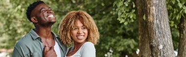 Neşeli Afro-Amerikan çifti el ele tutuşuyor ve dışarıda birbirlerine sarılıyorlar.