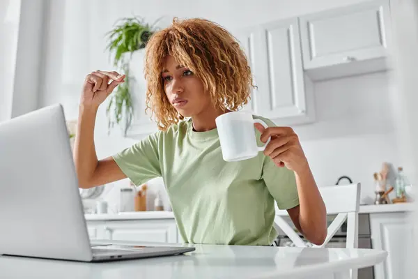 stock image serious african american woman using sign language during video call and holding cup, nonverbal