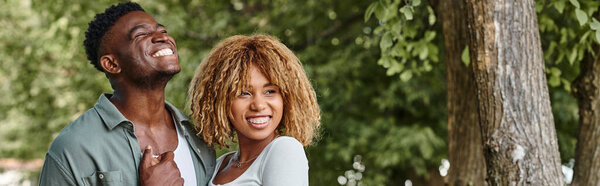 веселая африканская американская пара, держащаяся за руки и обнимающая друг друга на открытом воздухе, баннер