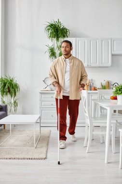 Güzel görünümlü kör Hintli adam rahat bir ev elbisesi içinde baston kullanıyor, engelli.