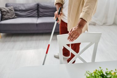 Gayri resmi kıyafetli kör Hintli adam mutfakta bastonunu kullanıyordu.