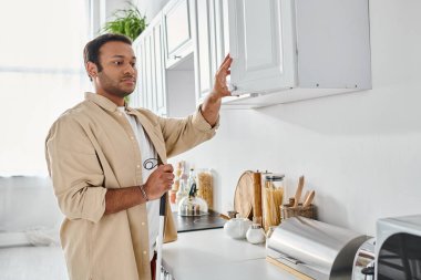 Yemek hazırlarken elinde baston tutan ev elbiseli çekici Hintli adam, kör.