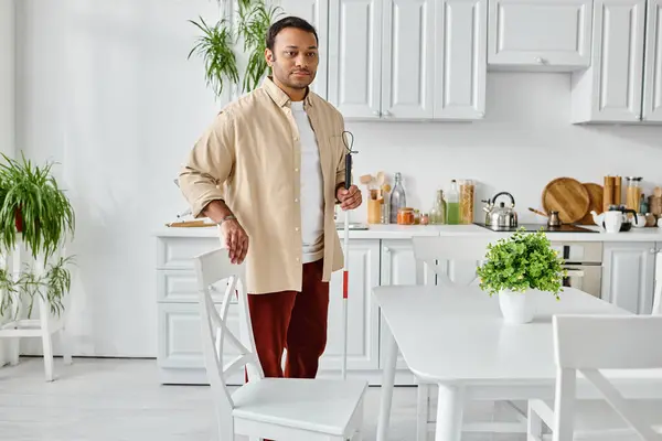 stock image handsome indian man with visual impairment in casual attire using walking stick at home, disabled