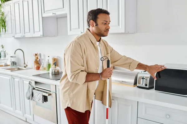 stock image attractive indian man with visual impairment wearing cozy homewear and preparing food, disabled