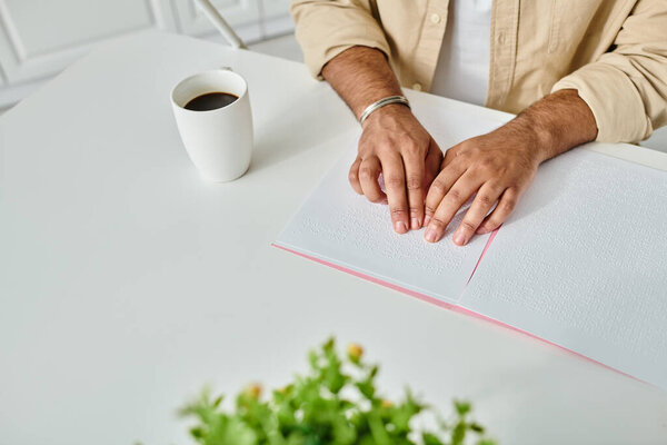 cropped view of indian blind man in comfy attire sitting at table reading braille code, disabled