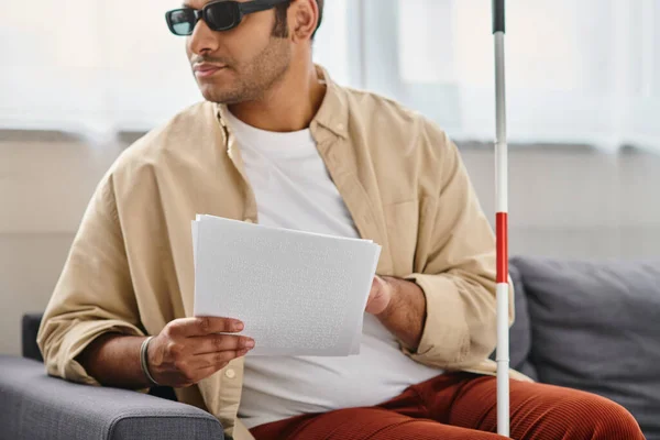 stock image merry indian man with visual impairment with glasses and walking stick reading braille code