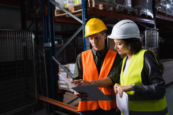 Два профессионала обсуждают за планшетом на складе, босс средних лет и его подчиненный