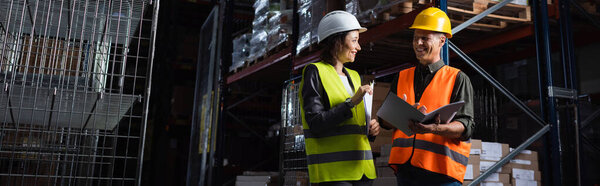 счастливые профессионалы в касках разговаривают на складе, босс среднего возраста и подчиненный, баннер