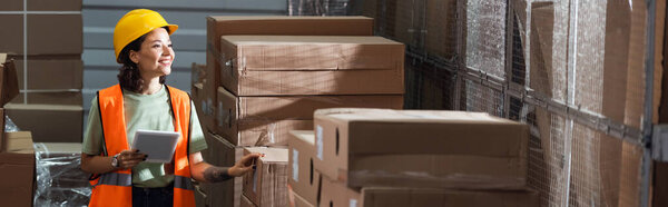 счастливая женщина-работница склада в спасательном жилете и каске с цифровым планшетом рядом с грузом, баннер