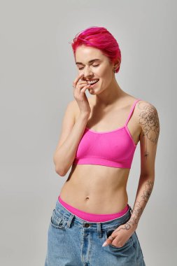 Ekin bluzlu, kot pantolonlu, cebinde poz veren neşeli, çekici kadın manken, moda anlayışı.