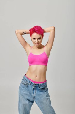 Pembe saçlı, dövmeli, poz veren ve kameraya bakan çekici bir kadın model. Moda anlayışı.