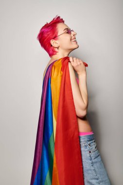 Lgbt gökkuşağı bayrağıyla poz veren pembe saçlı ve güneş gözlüklü kadın aktivistin yan görünüşü