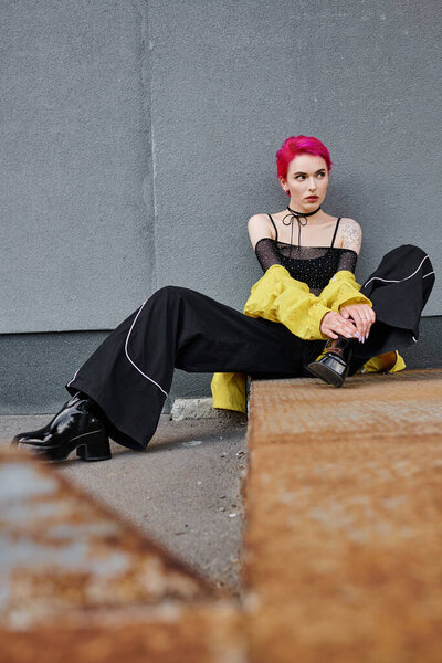 trendy young short haired woman with tattoos in stylish streetwear and looking away, fashion concept