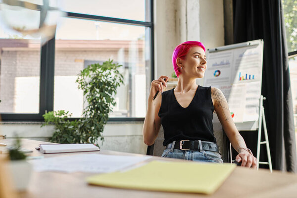 cheerful attractive businesswoman in casual outfit sitting and looking away with pen in hands