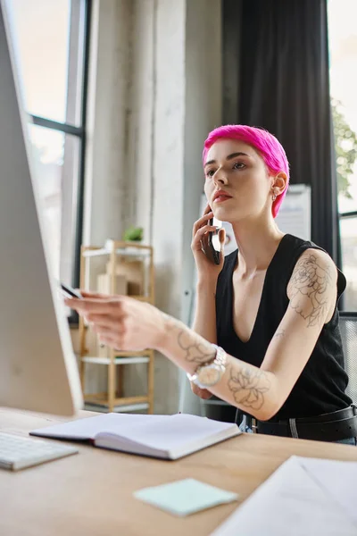 stock image attractive pink haired woman in casual attire talking by phone while working hard, business concept