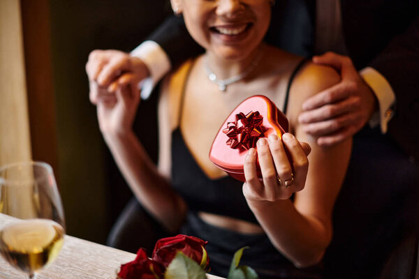 cropped man near happy african american woman holding heart-shaped box on Valentine`s day
