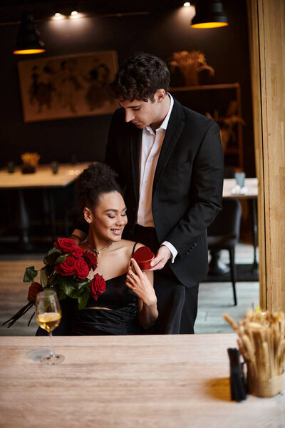 gentleman gifting heart-shaped box to cheerful african american woman with red roses on 14 February