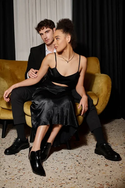 黒夜の多文化カップルは ベルベットソファーに座っている間一緒にポーズを着用 エレガンス — ストック写真