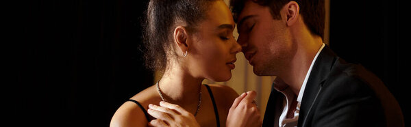 intimate moment banner, beautiful interracial couple in black attire kissing with closed eyes