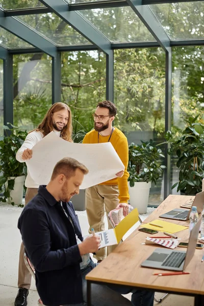 joyful appealing businessmen in casual outfit working attentively on their startup together