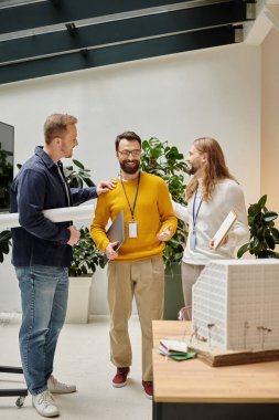 good looking jolly architects in casual attires working together on their startup, coworking concept clipart