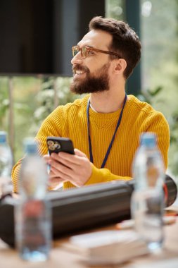 cheerful handsome architect in yellow turtleneck working on his startup and looking away in office clipart