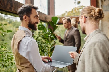 cheerful focused businessmen in elegant chic outfits discussing their project in their office clipart