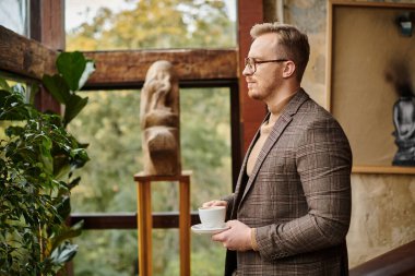 Seçkin takım elbiseli sofistike iş adamı sıcak kahvesini içiyor.