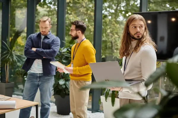 focus on bearded man in casual attire having videocall and his blurred colleagues discussing startup
