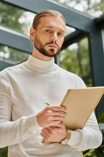 stock image focused handsome architect in white comfy turtleneck with beard holding his paperwork on startup