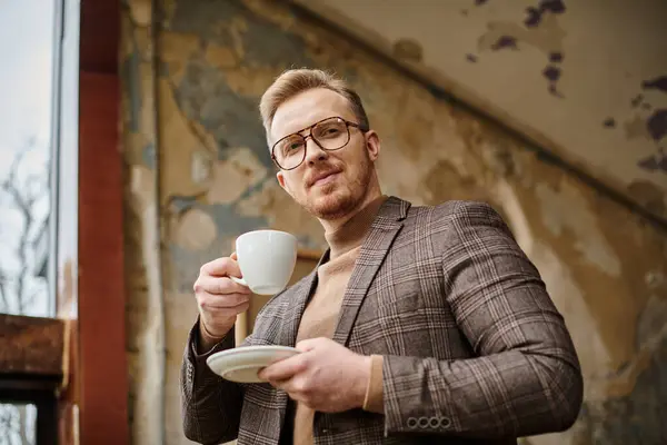 joyful sophisticated business leader with glasses in elegant chic suit drinking his hot coffee