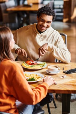 Mutlu çift, rahat bir kafede sıcak bir öğle yemeğinin tadını çıkarırken birlikte sakin bir anı paylaşıyor.