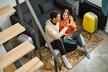 Neşeli siyah adam akıllı telefon ekranını işaret ediyor, kız arkadaşıyla heyecanlı bir anı paylaşıyor.