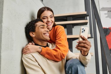 Mutlu çift merdivenlerde oturuyor ve gülümsüyor. Pansiyonda akıllı telefondan selfie çekiyorlar.