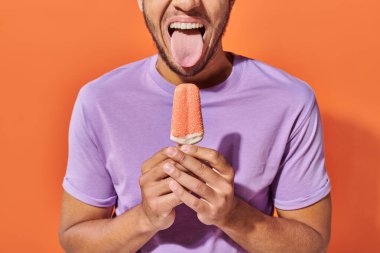 cropped african american man stinking put tongue and holding ice cream with sprinkles clipart