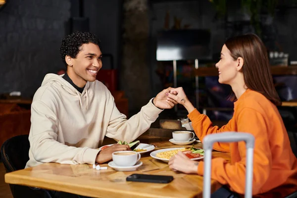 stock image cheerful diverse couple enjoying a delicious meal in the charming indoor restaurant, holding hands