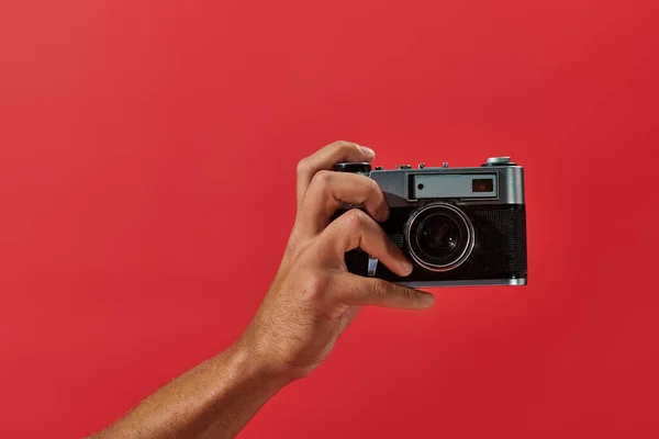 stock image cropped view of african american photographer taking shot on retro camera on red background