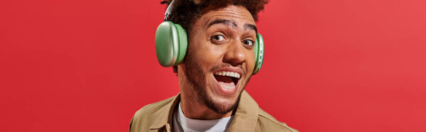 banner of excited african american man in wireless headphones with open mouth on red background