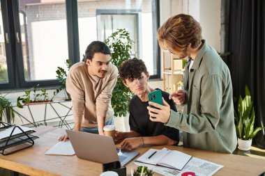 Three young professionals discussing a project and looking at smartphone while creating startup clipart